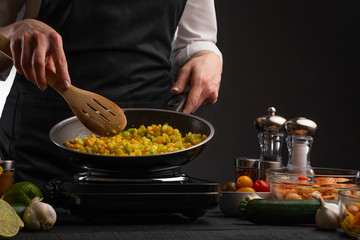 Chef cooks frying vegetables on the background of ingredients. Cooking, tasty and wholesome food. Book of home recipes.