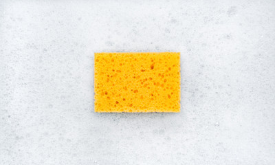 Clean, new sponge washcloth yellow in white soap foam. Clean house concept.