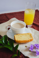 Cup of coffee with toast, orange juice and leaves on red background