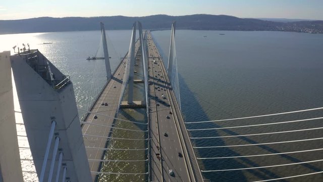 Drone passing through bridge towers, Cars driving on Hudson River, Mountains and City in the background. Aerial View 4K
