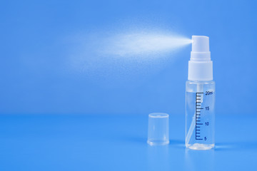 Personal pocket sanitizer on a blue background sprays a disinfectant. Virus protection.