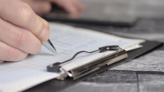 Hand writing on graph paper on clipboard close up panning shot