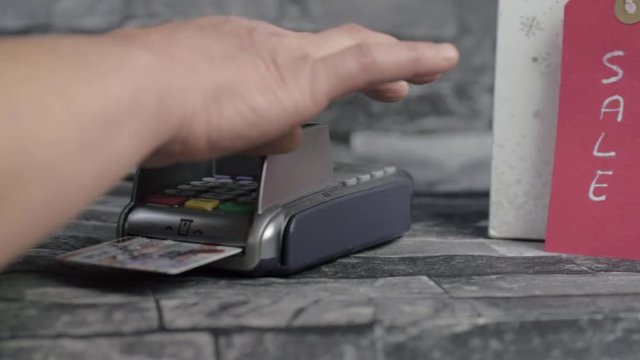 Hand using pdq payment machine to pay for goods in a sale medium panning shot