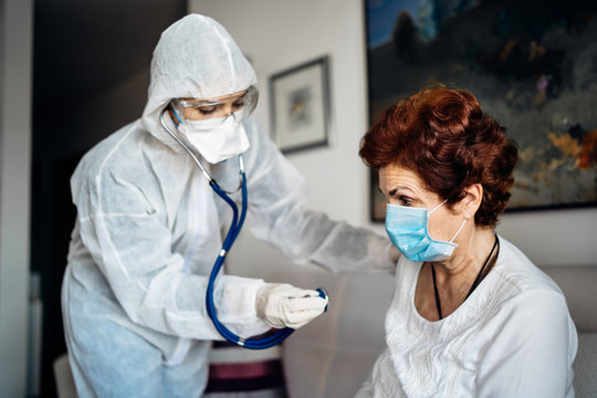 Home Care Doctor/nurse Listening To The Senior Patients’ Lungs With A Stethoscope.COVID-19 Patient Self Isolation Examination.Coronavirus Frontline Medical Worker In Home Visit To High Risk Patient