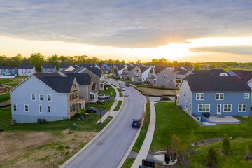Fototapeta na wymiar Aerial view of new American neighborhood street lined with large single family homes during sunset