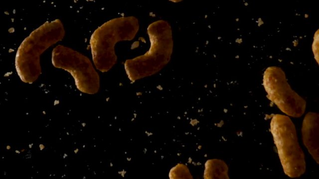 Peanut flips falling down in slow motion with black background surface