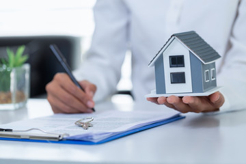 Gray roof house on the hands of businessmen or agents And signing the purchase contract House trading ideas Home insurance, investment, rental or purchase Real Estate and Mortgages.