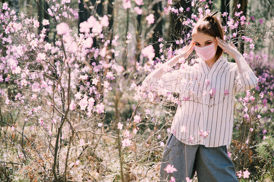 Girl in a medical mask among flowers