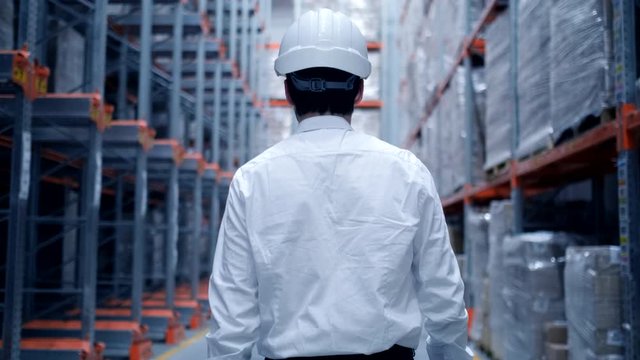 Follow footage of employees male warehouse worker engineer in hard hat working. walking through logistics center warehouse factory construction site logistics architect businessman man builder indoors