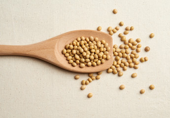 top view of soybean in wooden spoon on gunny textile background