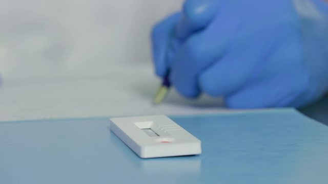 A laboratory technician documents the results of a finger-stick whole blood antibody test kit used to quickly determine a subject has been exposed to COVID19 in the past and has developed antibodies.