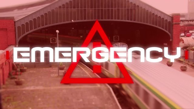 Word Emergency written over triangle warning road sign over train passing in the background. 