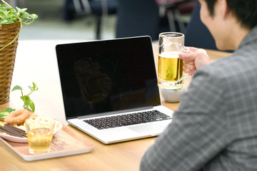 パソコンを見ながらビールを飲む男性