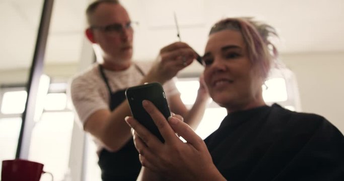 Low angle view woman using phone while hair styled