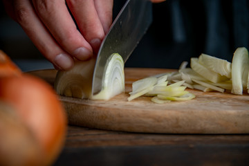Slicing onion on cutting board in kitchen.
Cooking image.