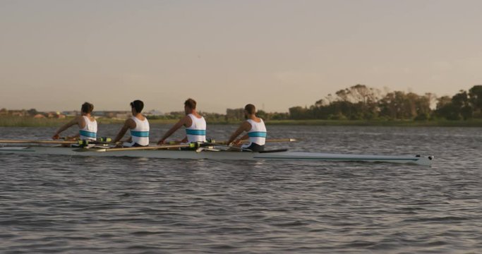 Side view of male rower team rowing on the lake