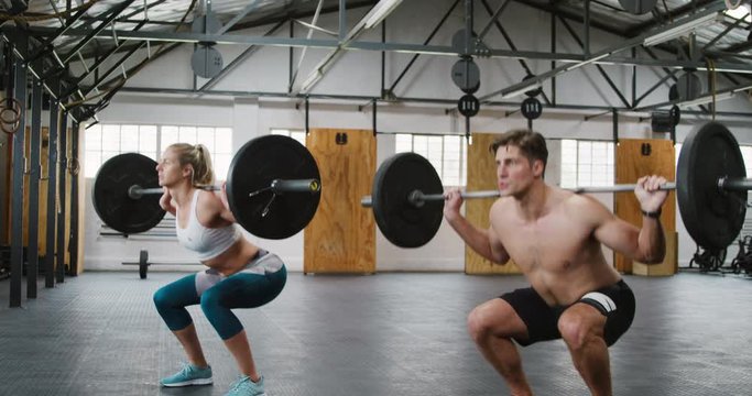 Side view of an athletic Caucasian man and woman squatting 