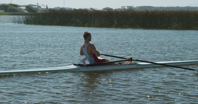 Side view of male rower practicing rowing on the lake
