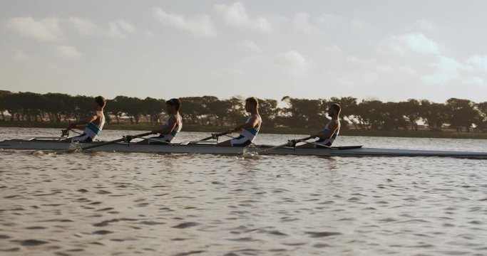 Side view of male rower team rowing on the lake