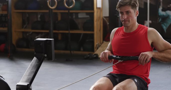 Front view athletic Caucasian man exercising on a rowing machine