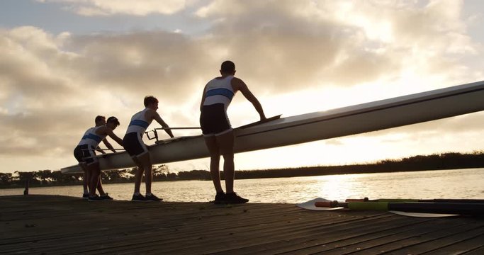 Male rower team taking out of the lake the boat