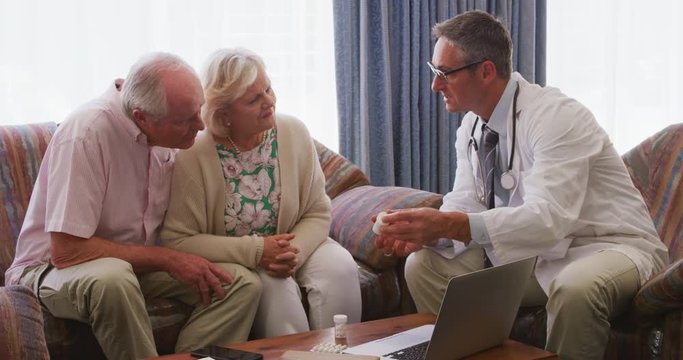 Senior couple talking with a doctor in retirement house