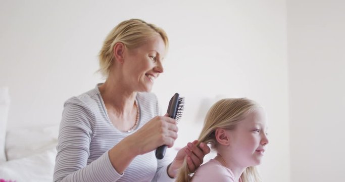 Side view of Caucasian woman brushing hair of her daughter