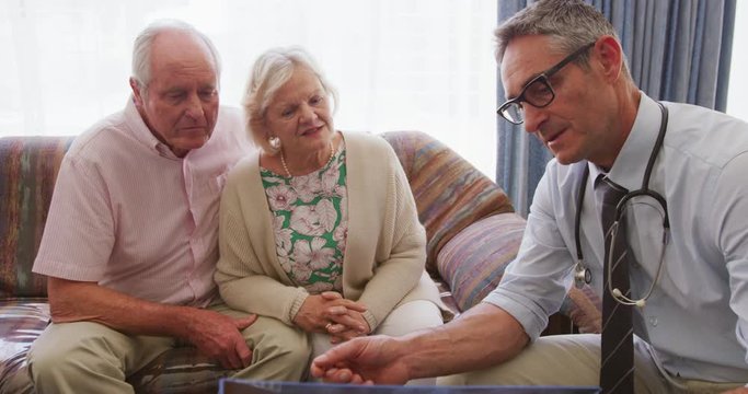Senior couple talking with a doctor in retirement house