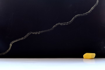 Black chalkboard with ascending chart and piece of chalk on white desk. Mock up school and business concept background with copy space