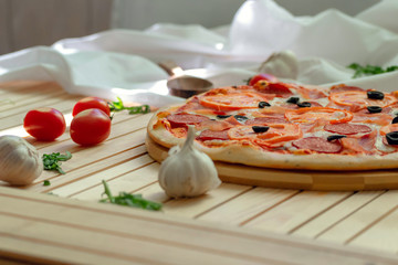 pizza with salami and tomatoes on wooden background
