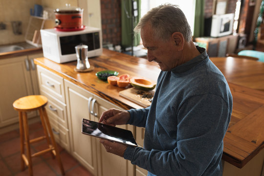 Senior man using digital tablet on his kitchen