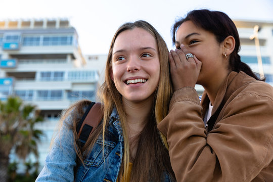 Front view of girl telling a secret to her friend