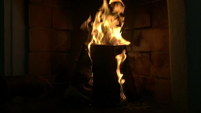 Fire place close up. Fire flames burning in slow motion in the dark. Bonfire and wood burning. Bricks wall on the background