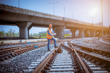 Naklejka premium Portrait engineer under inspection and checking construction process railway switch and checking work on railroad station .Engineer wearing safety uniform and safety helmet in work.