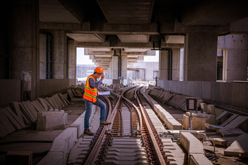 Fototapeta premium Portrait engineer under inspection and checking construction process railway switch and checking work on railroad station .Engineer wearing safety uniform and safety helmet in work.