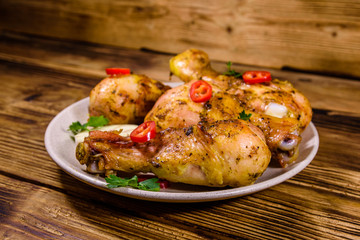 Baked chicken legs with parsley, garlic and sliced red hot pepper in a plate