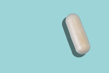 Medical pill, pharmaceutical medicine capsule. Painkiller, vitamin, antibiotic, probiotic on blue background.