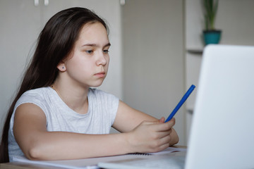 Teenager girl at a table with a white laptop.