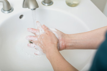 Person washing their hands at with soap and water for coronavirus prevention