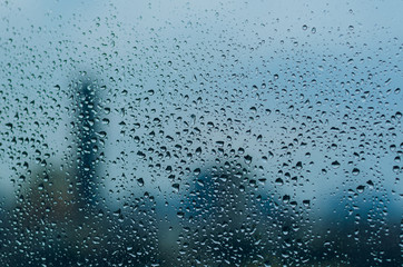 Rain drop on glass window in monsoon season with blurred city background for abstract and background concept.