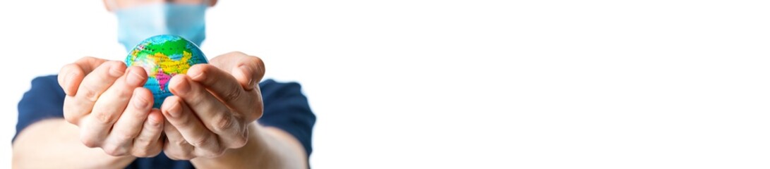 Banner. Close-up of a man's hands holding a globe, with images Russia, China, India, a man in a medical mask out of focus, dressed in a t-shirt, uniform on a white isolated background. Coronavirus