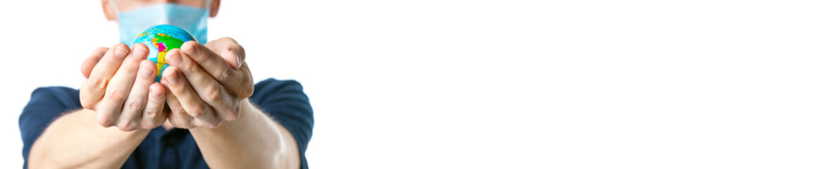 Banner. Close-up of a man's hands holding a small globe, with images South America:Brazil, Peru, a man in a medical mask out of focus, dressed in a t-shirt, on a white isolated background. Coronavirus