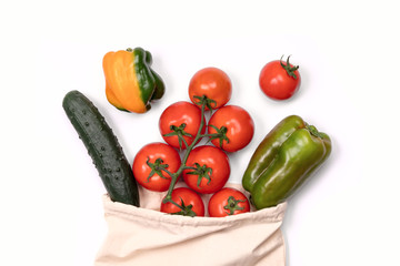 Summer vegetables in reusable eco friendly cotton bag on white. Zero waste, plastic free shopping, ecological concept.