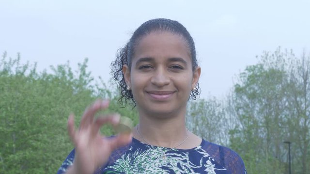 Woman holds physical Bitcoin in front of her Eye