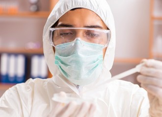 Young biochemist wearing protective suit working in the lab