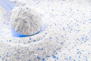 Clean detergent. White wash powder texture in cup or scoop for washing machine. Liquid soap laundry background. Eco style cleaning concept.
