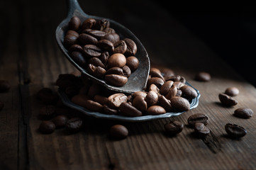  coffee beans on old rusty spoon on wooden background