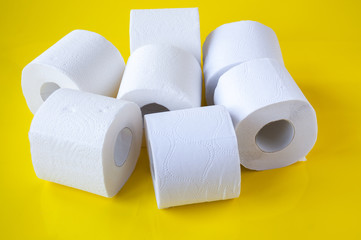 A pile of rolls of white toilet paper on a yellow background
