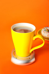 Cup of coffee with heater on color background