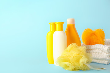 Shower gels, towels and loofah on color background